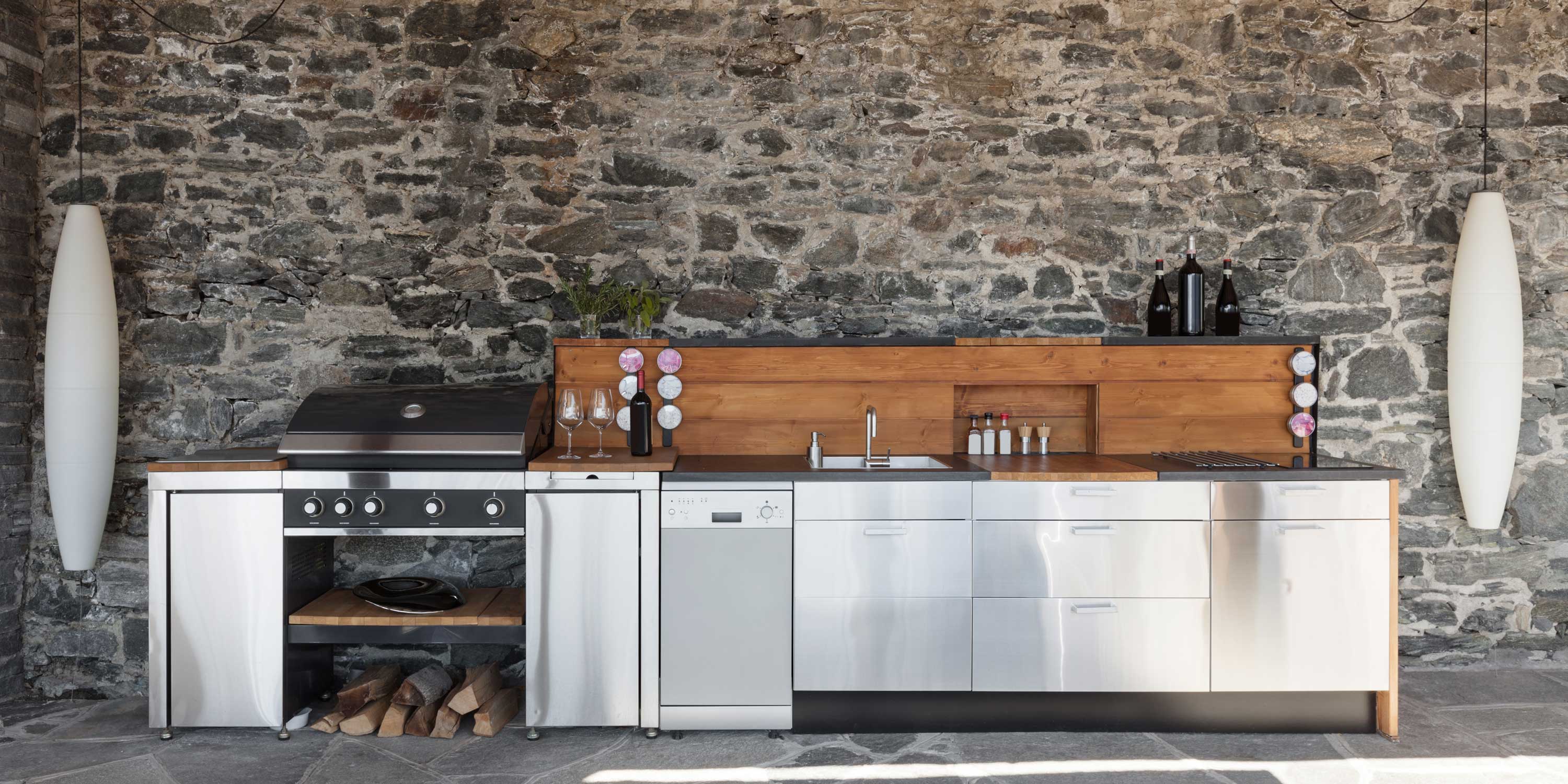 outdoor kitchen with stainless steel and a stone background